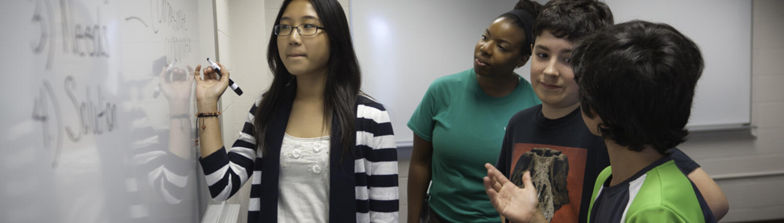 photo of students working on a problem on a whiteboard